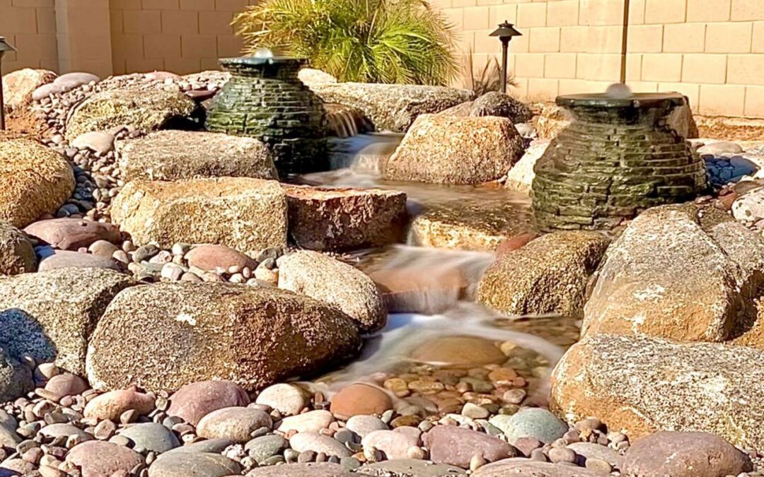 A tiered waterfall with river rocks and two vase shaped fountains.