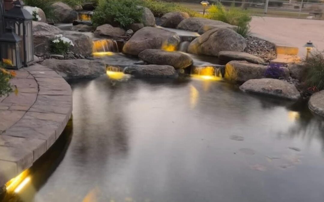 A koi pond with added natural rock waterfalls and lighting.