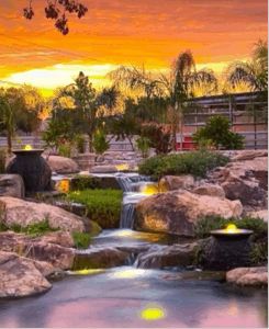 A stunning sunset illuminates a waterfall cascading over rocks, creating a serene and picturesque landscape.
