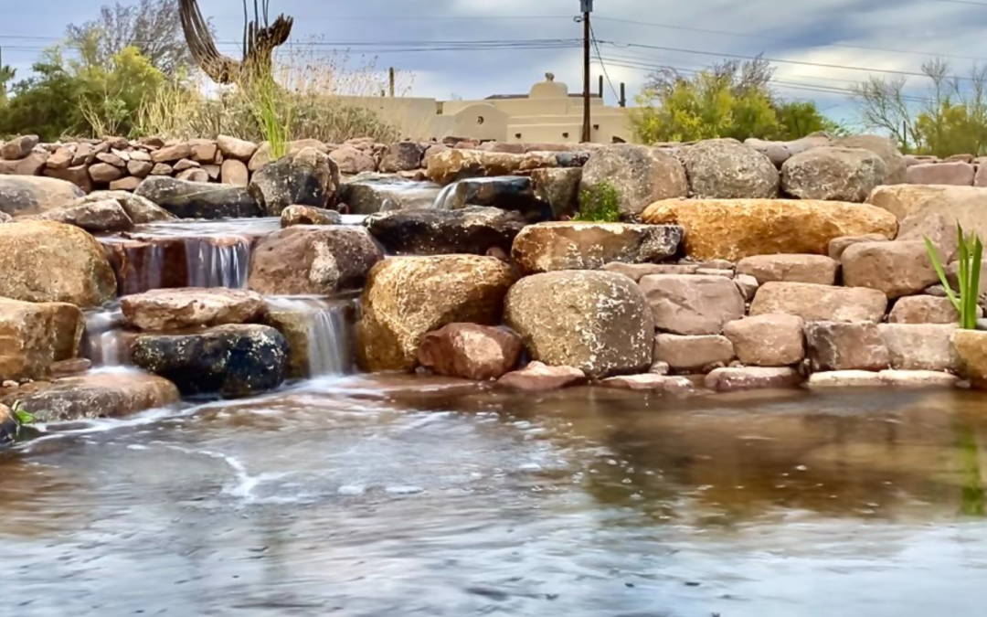A large pond in Arizona with a cascading waterfall pouring into it.