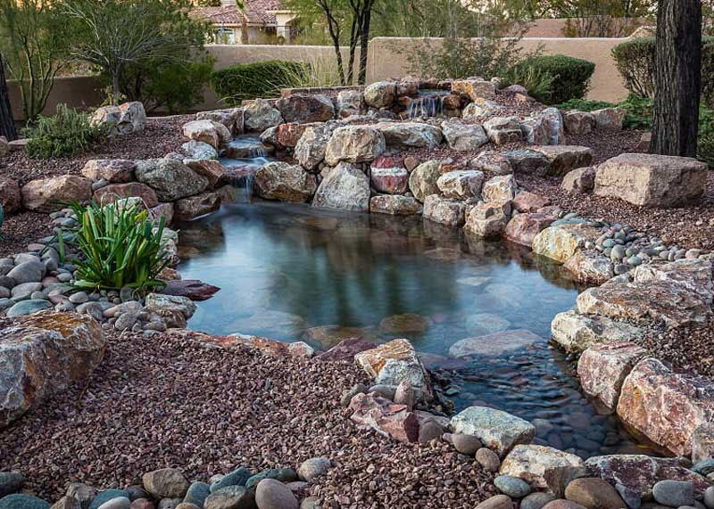 A small pond with a small waterfall pouring into it in a backyard in Scottsdale, Arizona.